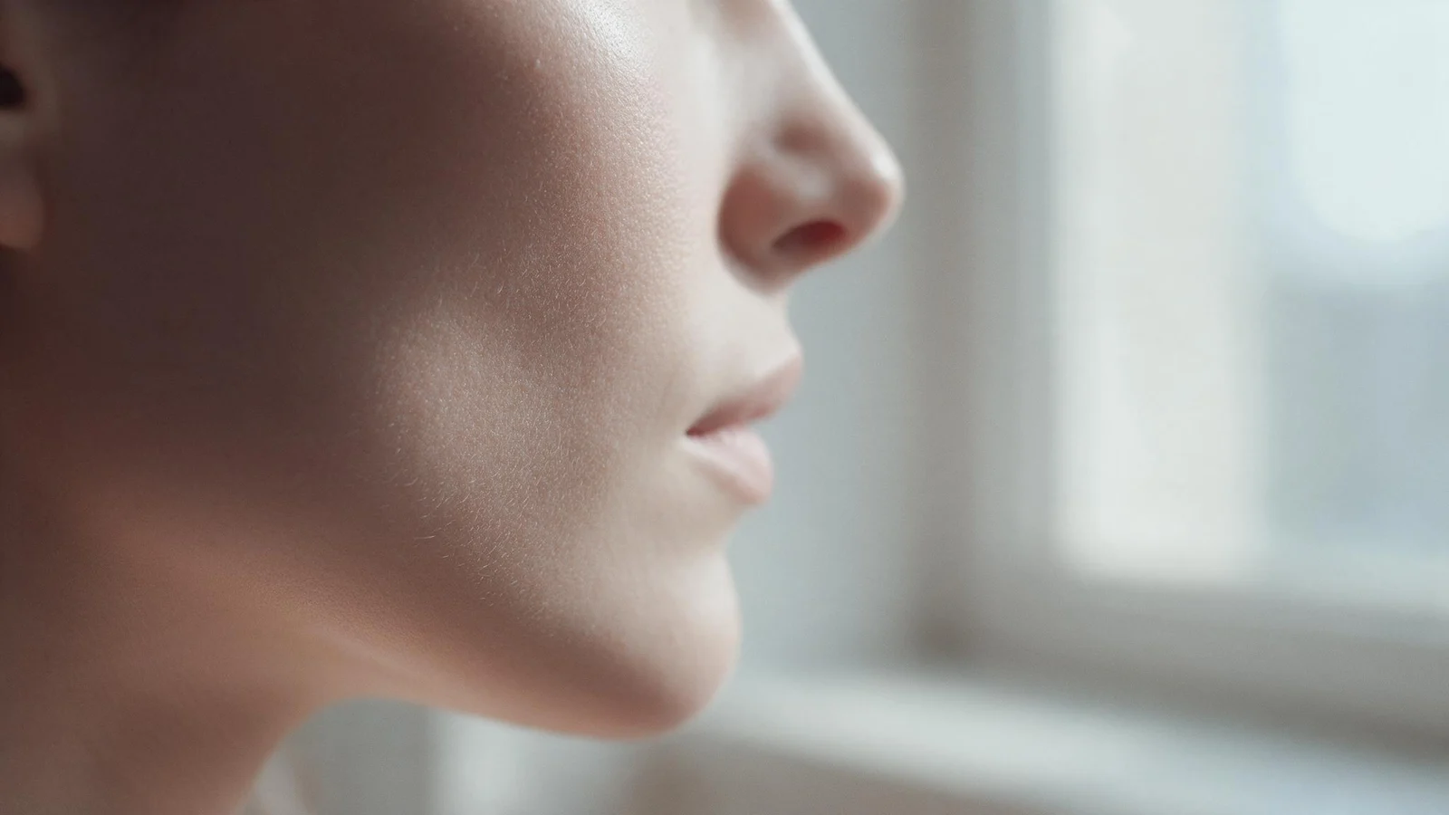 Close-up of a woman’s cheek and skin in soft morning window light